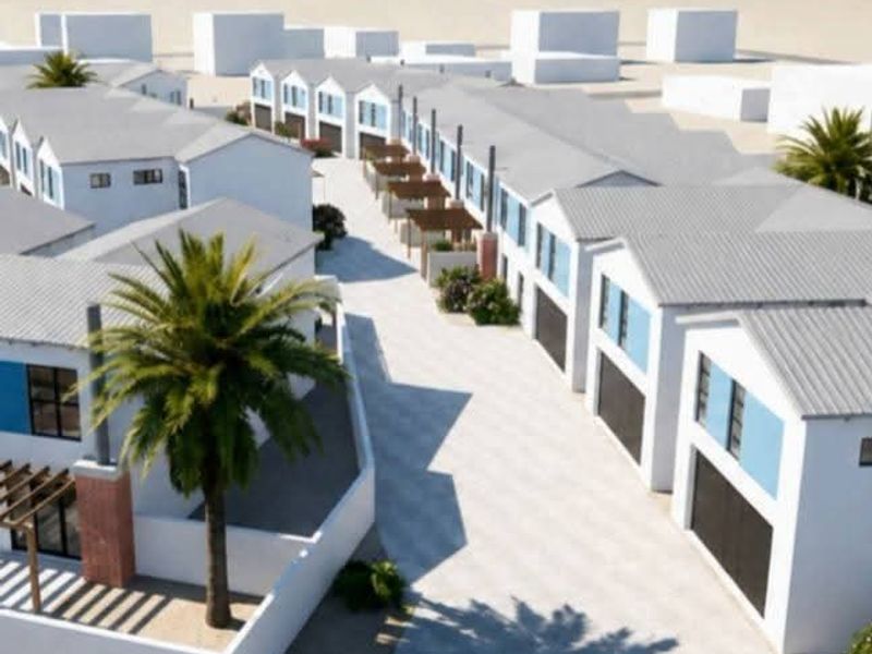 Aerial view of a modern residential estate featuring multiple townhouses with pitched roofs, paved driveways, and integrated garages near the coast.