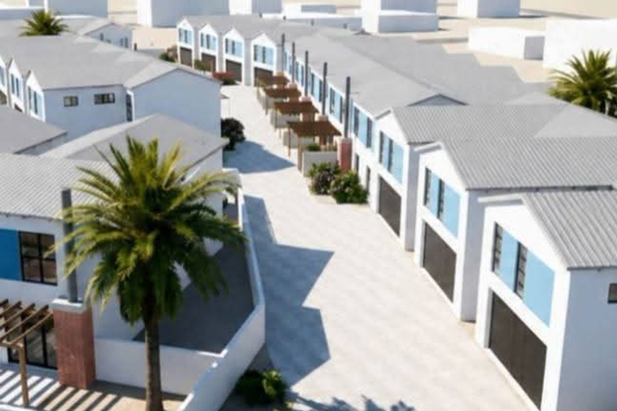 Aerial view of a modern residential estate featuring multiple townhouses with pitched roofs, paved driveways, and integrated garages near the coast.