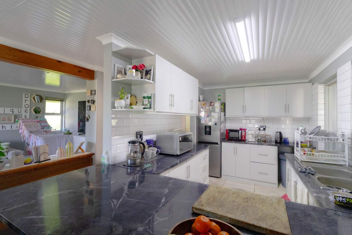 A functional kitchen featuring white cabinetry, dark stone countertops, subway tile backsplash, and a beaded ceiling, offering a clean and practical workspace.