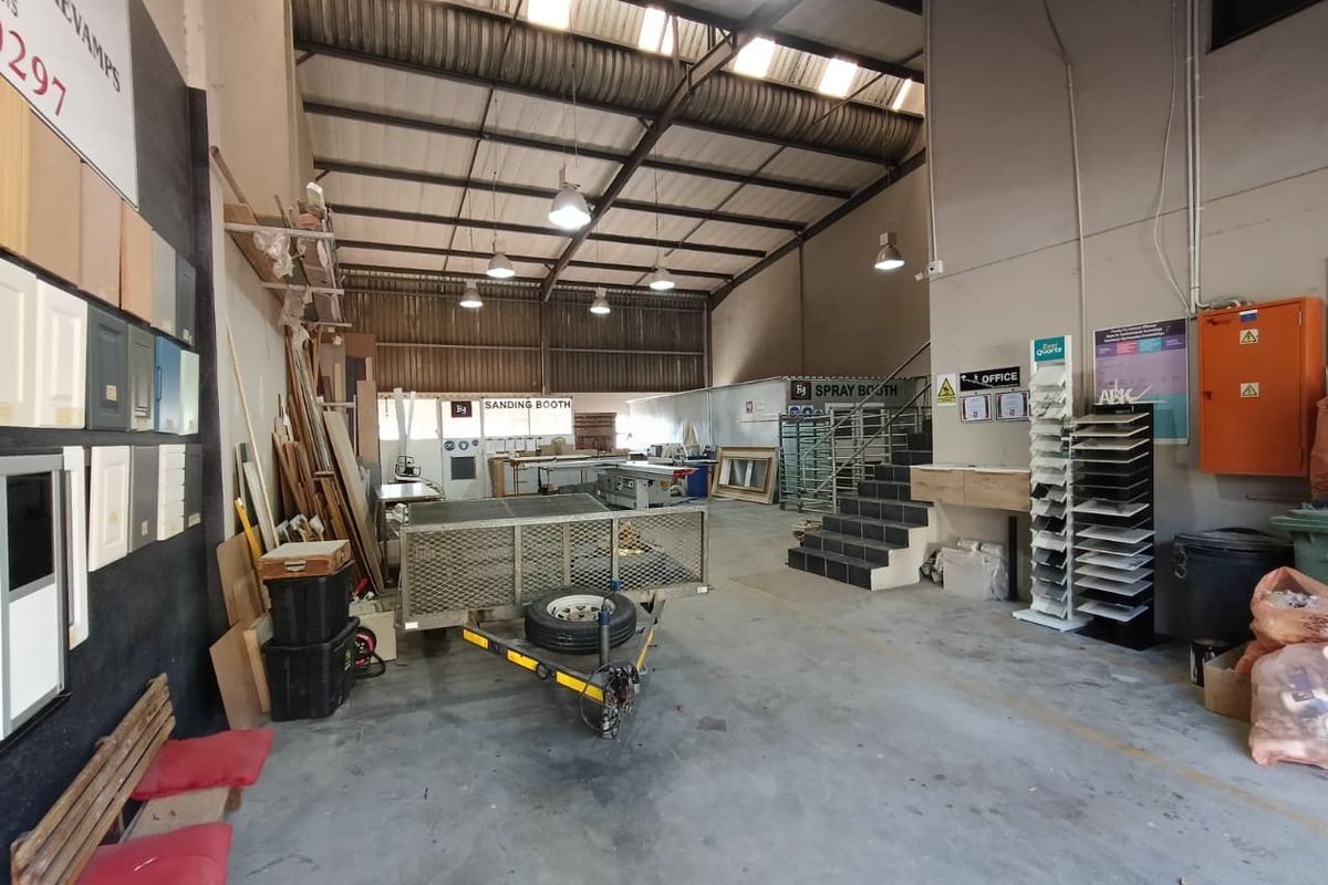 Spacious industrial workshop area featuring high ceilings, concrete flooring, and integrated utility zones including a designated sanding and spray booth.