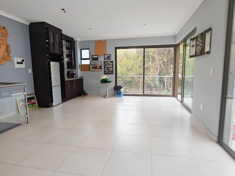 Spacious living area featuring tiled flooring, built-in bar cabinetry, and large sliding glass doors opening to a balcony with scenic views.