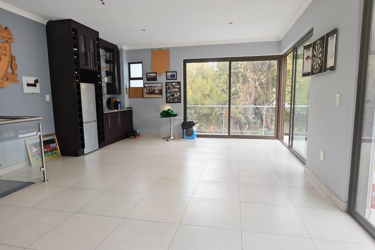 Spacious living area featuring tiled flooring, built-in bar cabinetry, and large sliding glass doors opening to a balcony with scenic views.