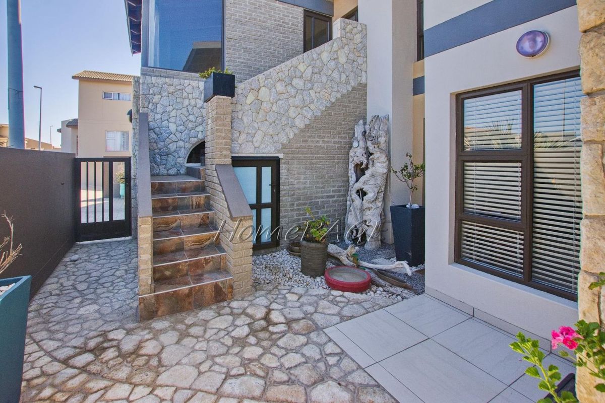 A well-maintained rear courtyard featuring stone-clad walls, a tiled staircase, and paved flooring, providing a structured and attractive outdoor transition area.