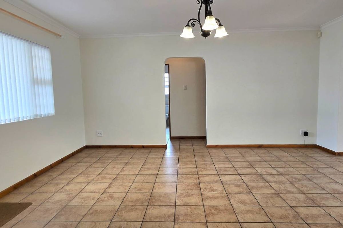 Spacious living area featuring neutral walls, tiled flooring, a built-in media cabinet, and a classic chandelier, offering a versatile layout for family living.