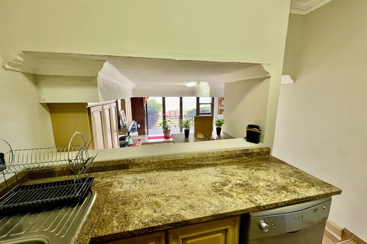Kitchen featuring granite countertops and a pass-through window overlooking the adjacent living area, providing an open-plan feel with views toward the exterior.