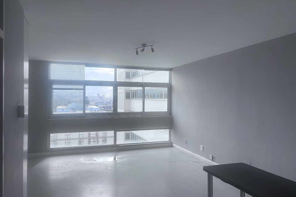 A bright and spacious empty living area featuring large windows that provide ample natural light and an urban view.