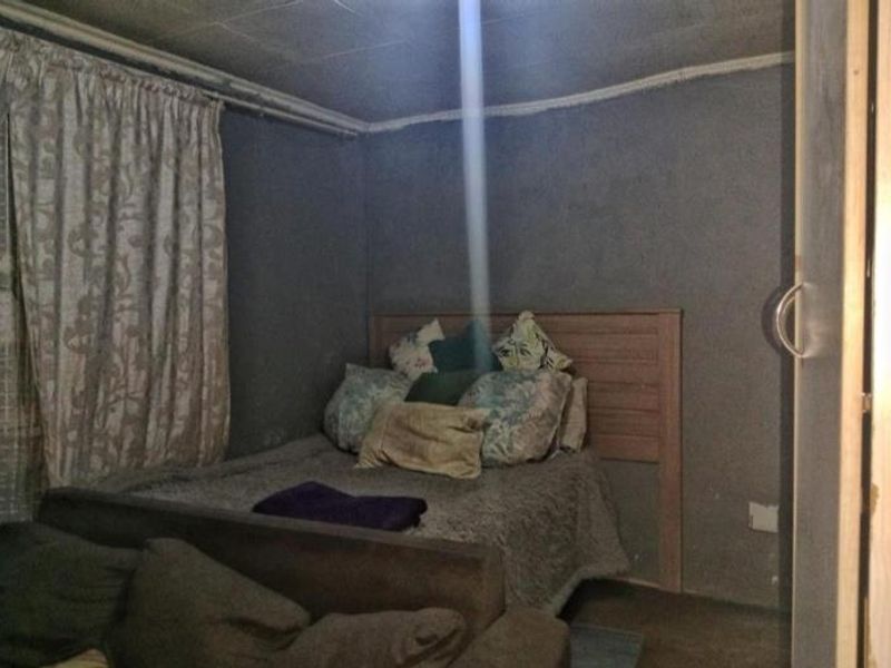 A compact bedroom featuring a built-in cupboard and basic finishes, offering potential for cosmetic updates to enhance the living space.