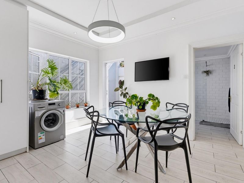Bright dining area featuring modern tiled flooring, recessed ceiling lighting, and built-in cabinetry, with direct access to an adjacent bathroom.