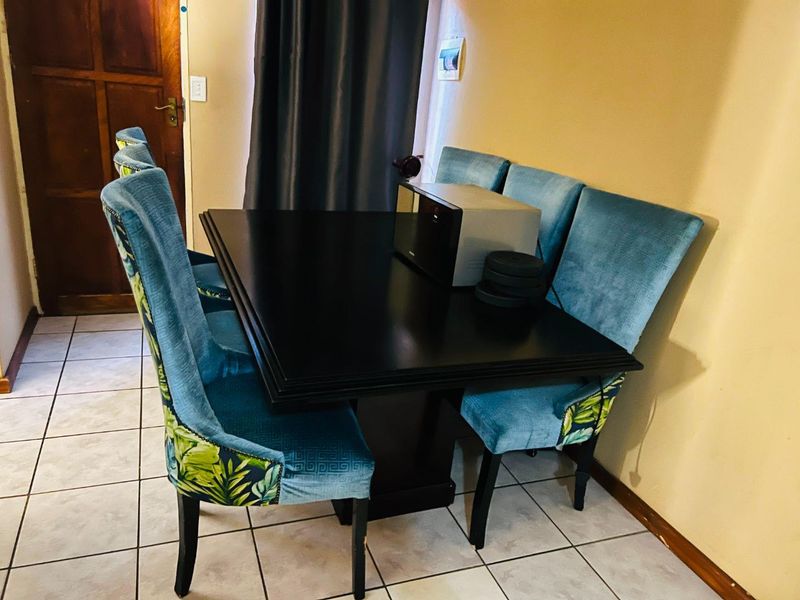 A dining area featuring tiled flooring and a wooden door, providing a functional space for meals.
