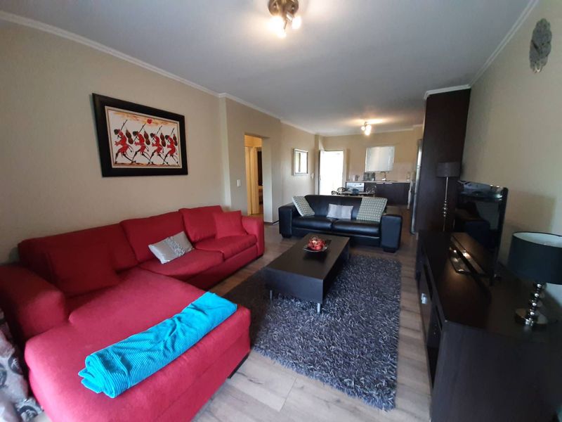 Open-plan living area featuring laminate flooring and a connected kitchen space, providing a functional layout for modern apartment living.