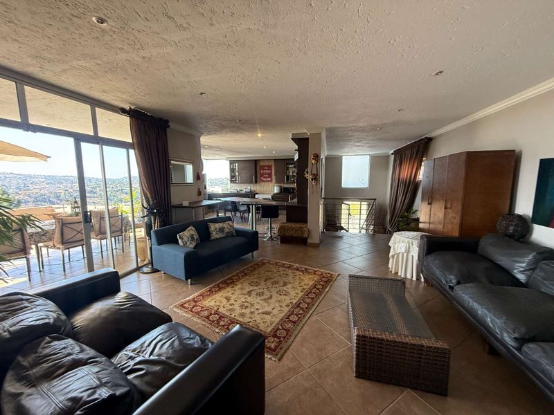 Spacious open-plan living area featuring tiled floors, recessed lighting, and seamless flow to an outdoor patio with expansive views.