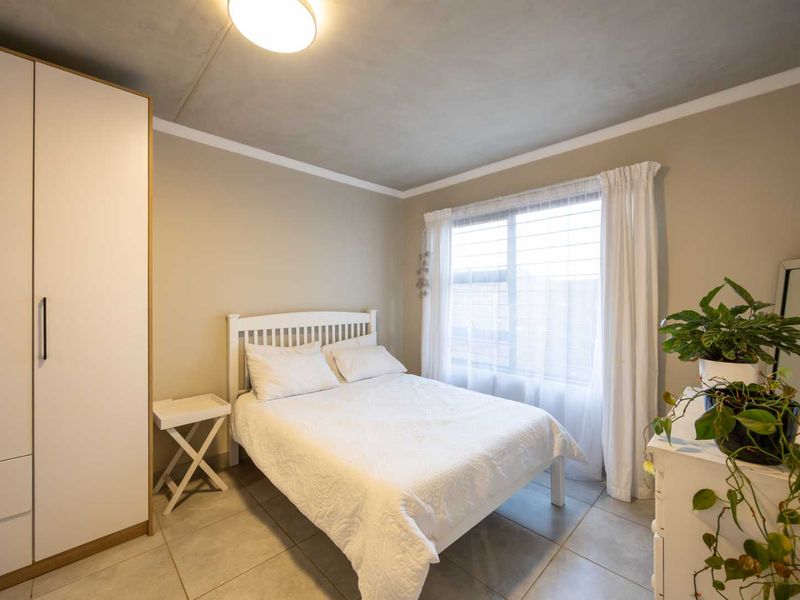 A well-maintained bedroom featuring neutral wall tones, tiled flooring, and a built-in wardrobe, offering a clean and functional living space.