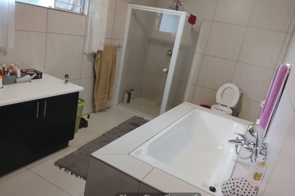 A functional bathroom featuring a built-in vanity, a separate shower enclosure, a bathtub, and tiled finishes throughout.