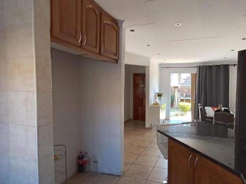 Open plan living area featuring a kitchen with granite countertops and wooden cabinetry, flowing into a dining space with direct access to the garden.