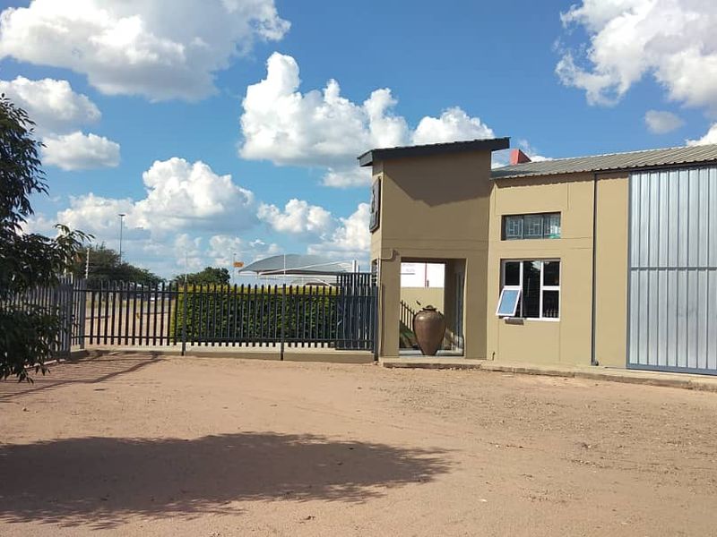 Front exterior view of an industrial property featuring metal cladding, secure perimeter fencing, and a gated entrance.
