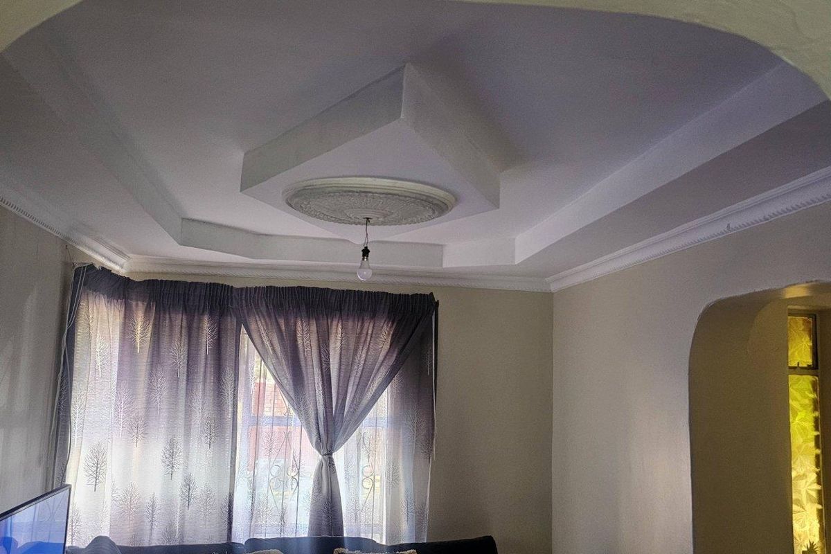 A living room featuring a decorative tray ceiling with a central medallion and an arched entryway leading to an adjacent space.