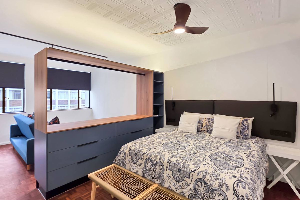 A well-maintained bedroom featuring parquet flooring, a decorative ceiling, a built-in room divider with integrated storage, and a modern ceiling fan.