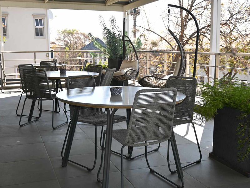 A spacious covered balcony featuring tiled flooring and a modern stainless steel railing, providing an ideal outdoor area for office staff breaks.