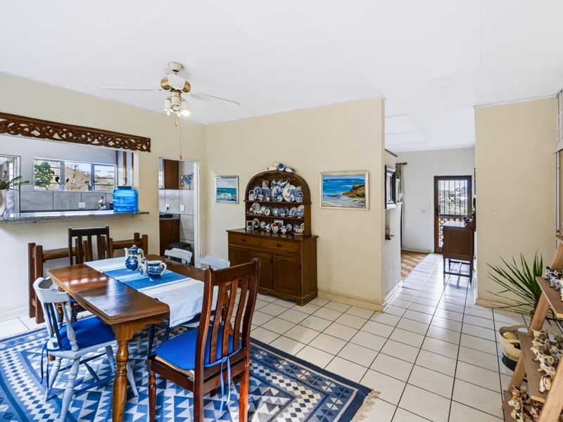 Open plan dining area featuring tiled flooring, a ceiling fan, and a convenient pass-through window connecting to the kitchen area.