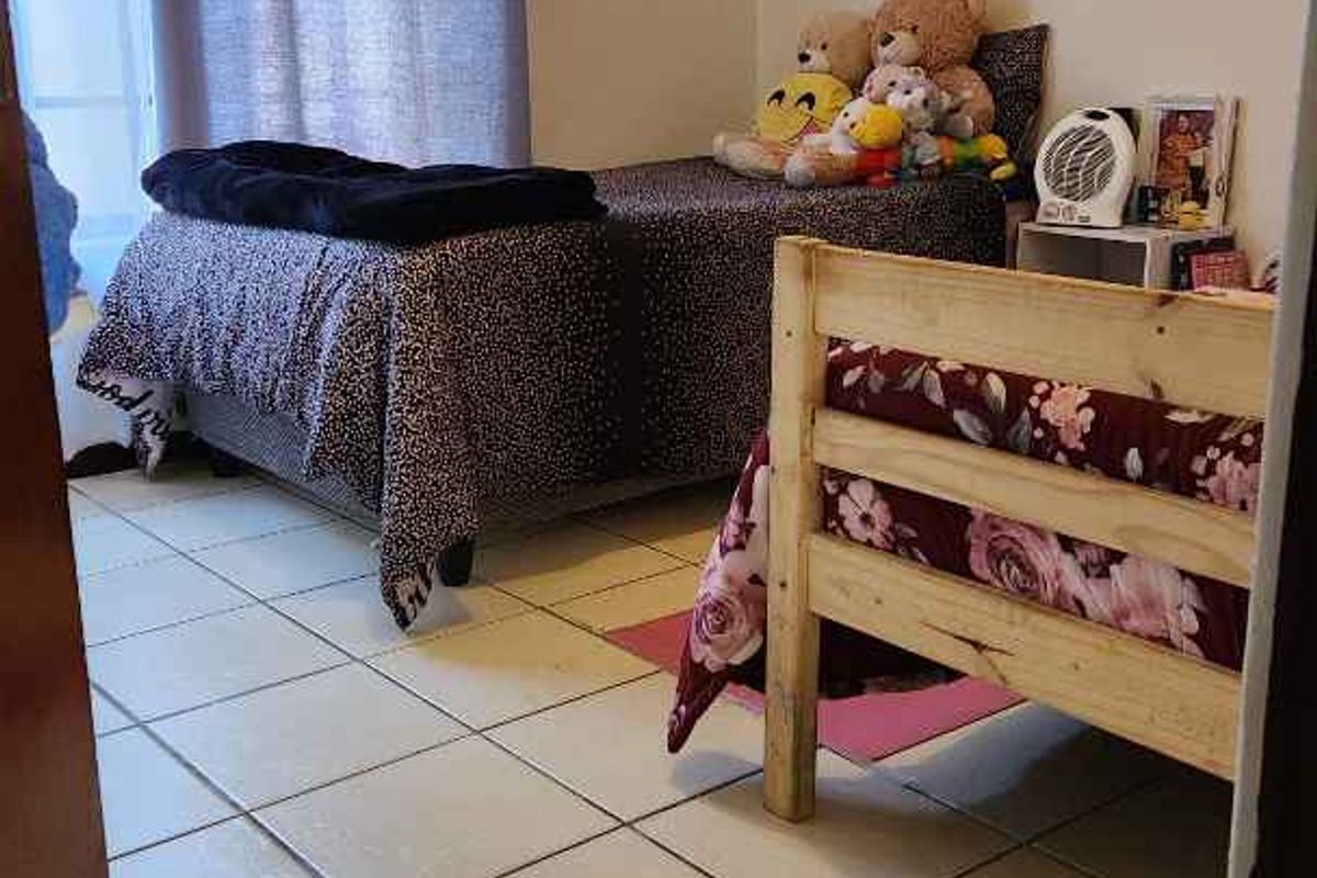 A bedroom featuring tiled flooring and a window with curtain treatments.