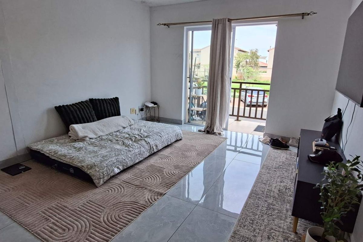 A living room featuring tiled flooring and a sliding glass door providing access to a balcony.