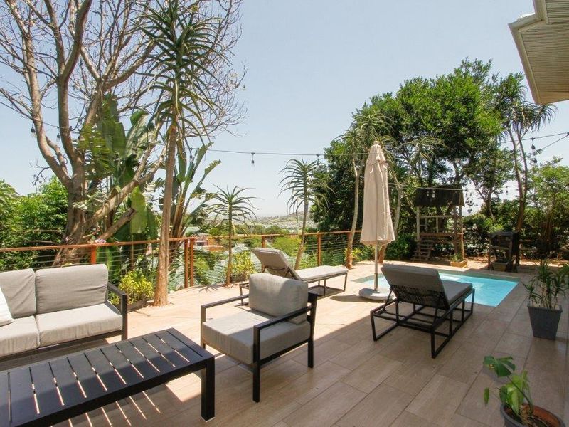 A spacious outdoor patio featuring a tiled deck, cable railing, and a swimming pool, offering an elevated view of the surrounding area.