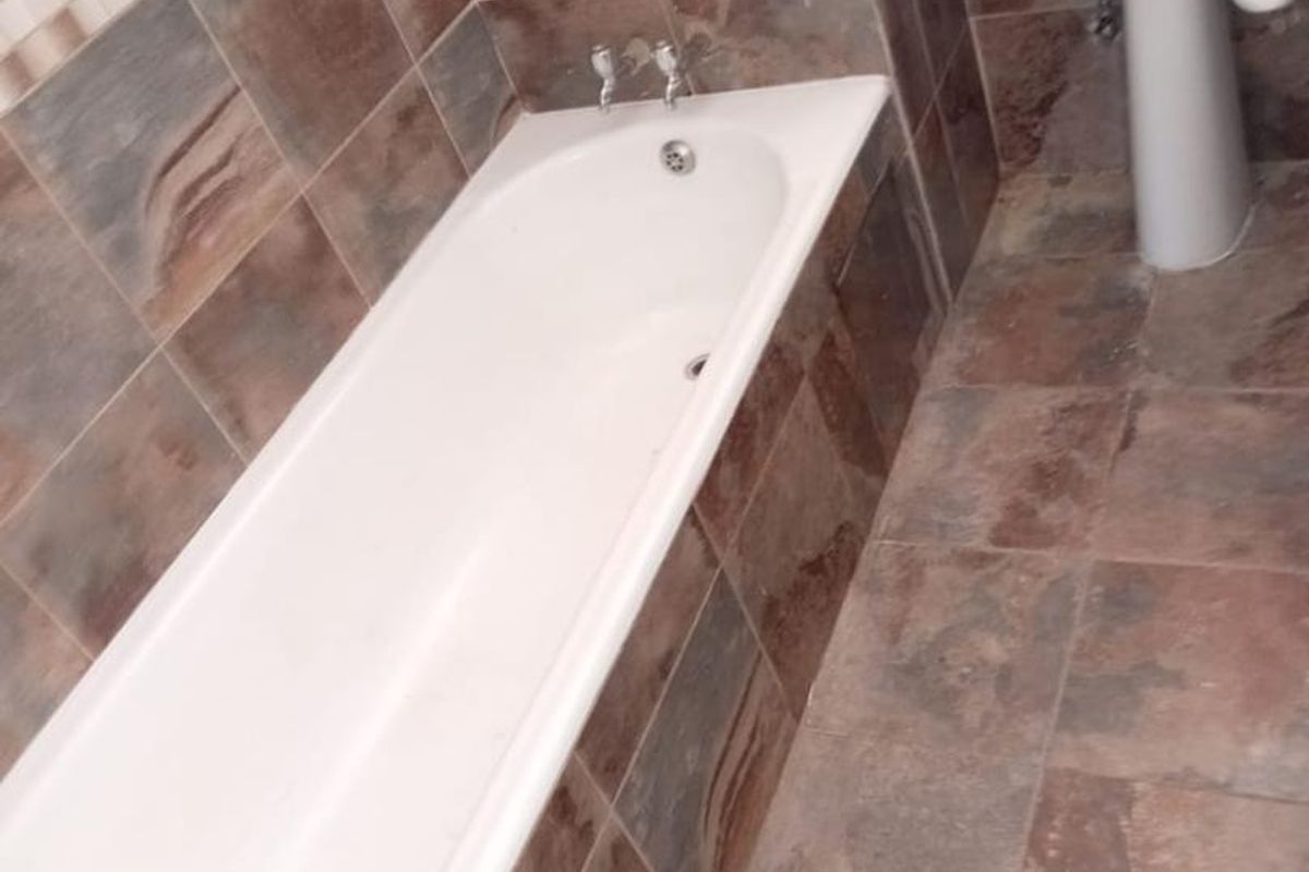 A bathroom featuring a built-in bathtub and a pedestal basin with full-height wall tiling and floor tiles.