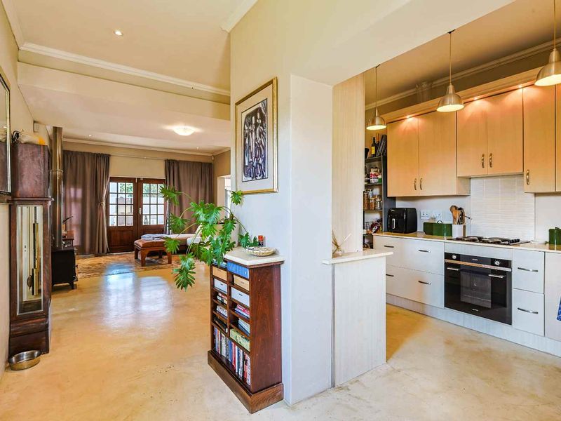 An open-plan living area featuring a functional kitchen with built-in appliances and a spacious lounge area with access to the outdoors.