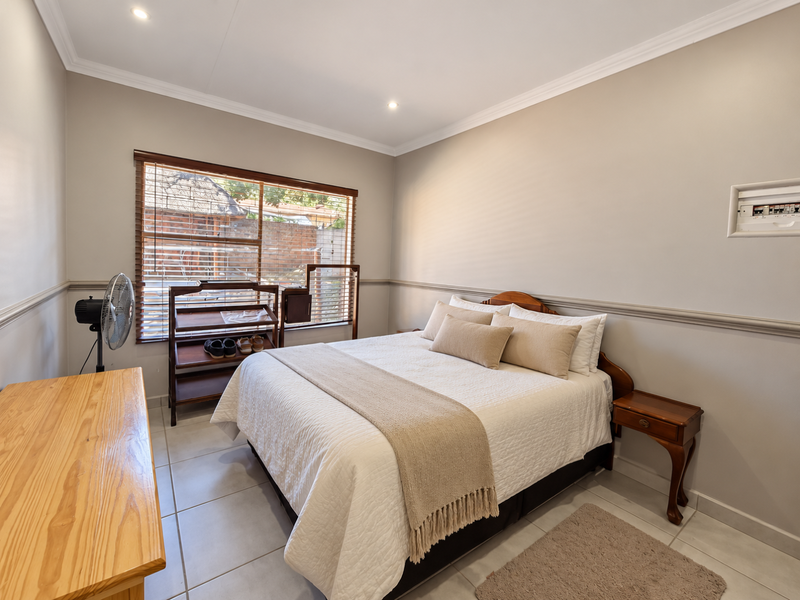 A well-maintained bedroom featuring tiled flooring, crown molding, chair rail detailing, and recessed lighting, providing a clean and functional living space.
