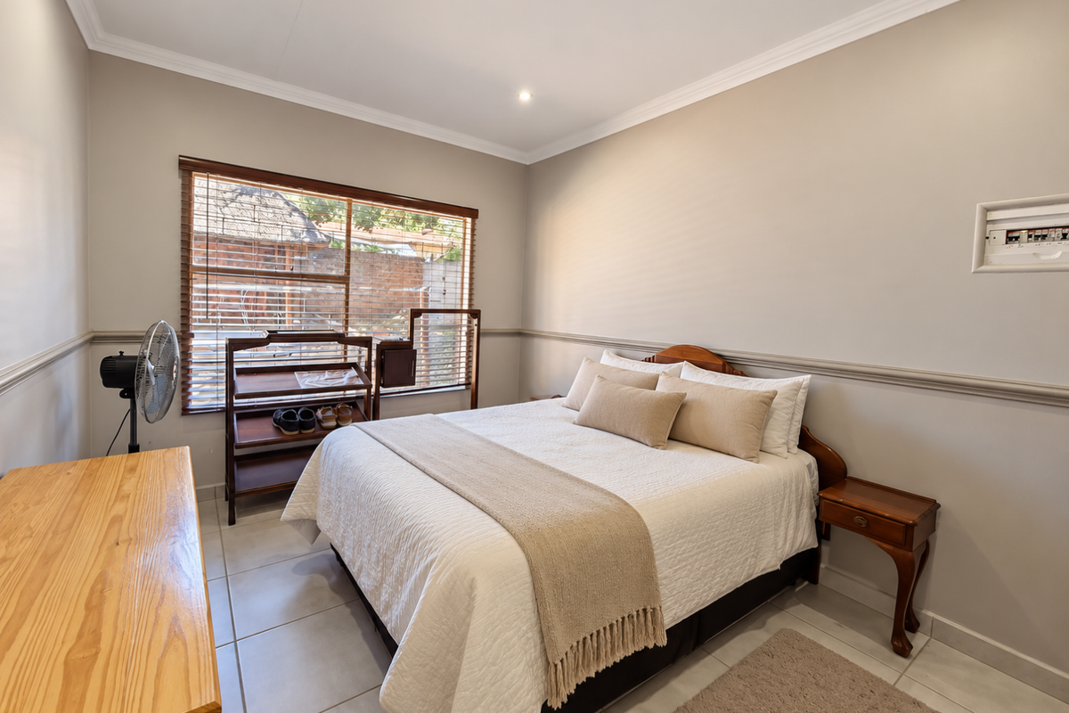 A well-maintained bedroom featuring tiled flooring, crown molding, chair rail detailing, and recessed lighting, providing a clean and functional living space.