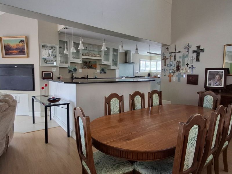 Spacious open-plan living and dining area featuring a functional kitchen with a breakfast bar, granite countertops, and modern pendant lighting.