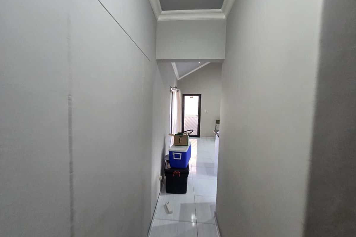 A clean, neutral-toned hallway featuring tiled flooring and coved ceiling details, providing a clear transition between living spaces.