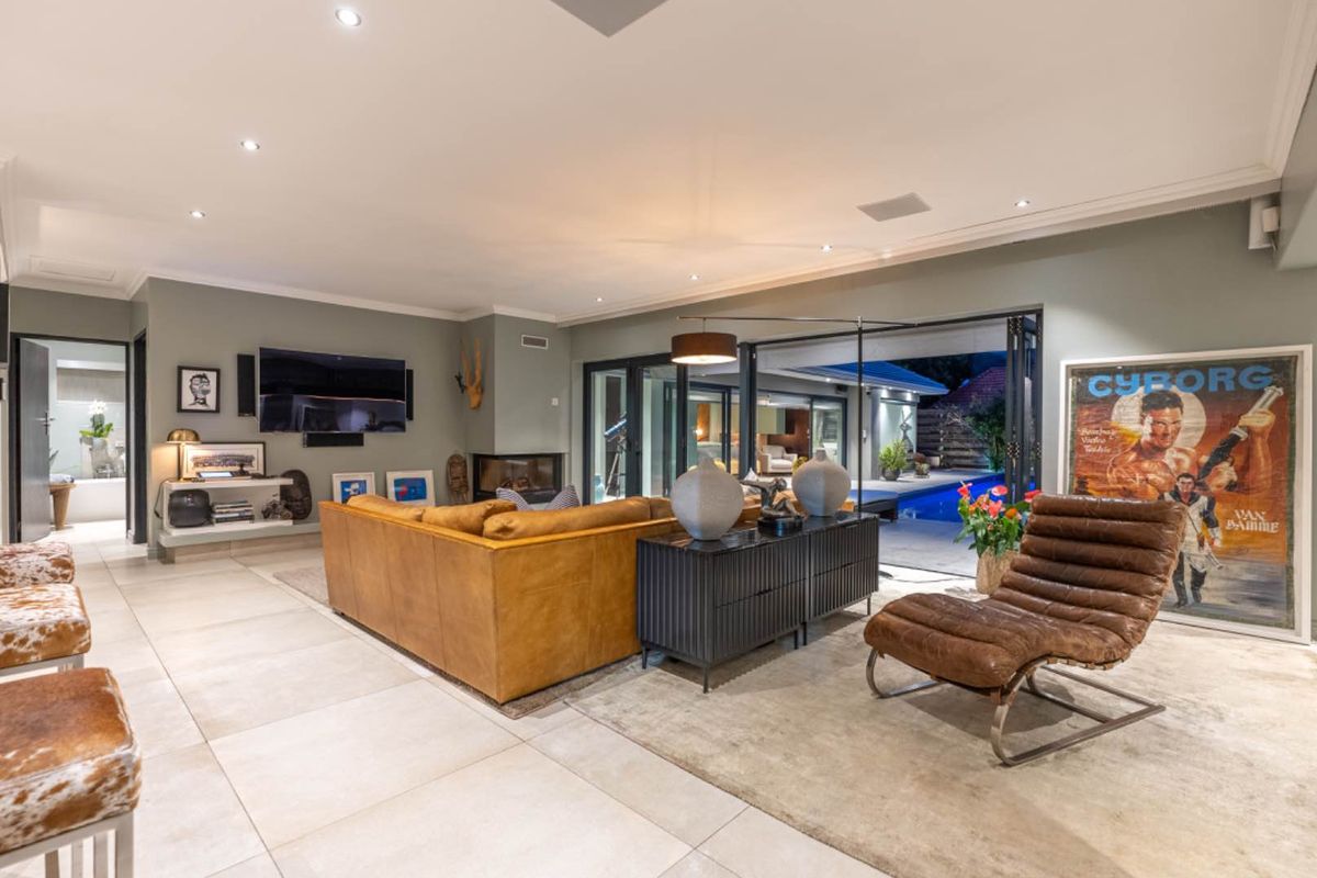 Spacious living room featuring large format floor tiles, a built-in fireplace, and seamless indoor-outdoor flow through bi-fold doors leading to the pool area.