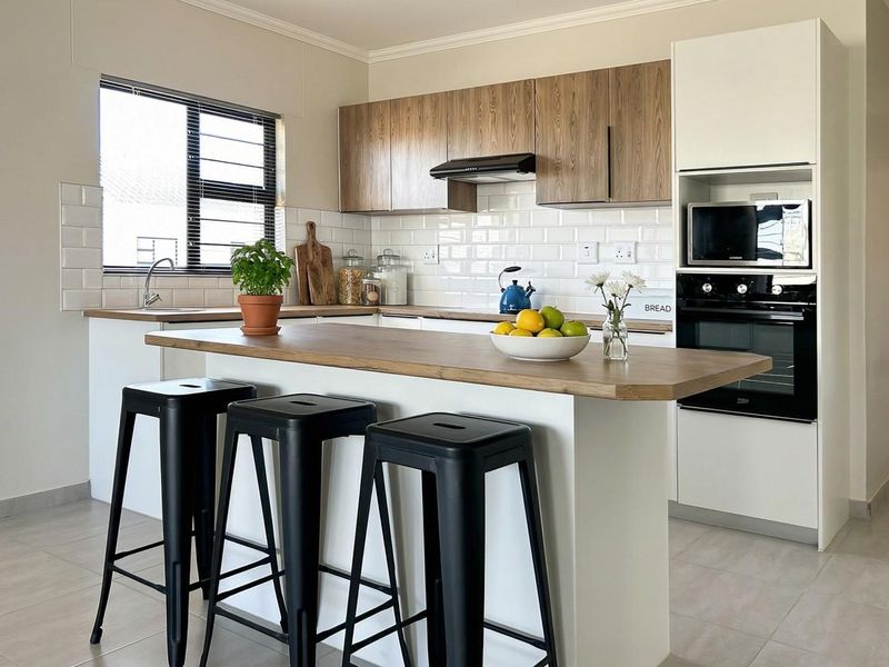 Modern kitchen featuring wood-tone and white cabinetry, subway tile backsplash, built-in appliances, and a functional breakfast island with tiled flooring.