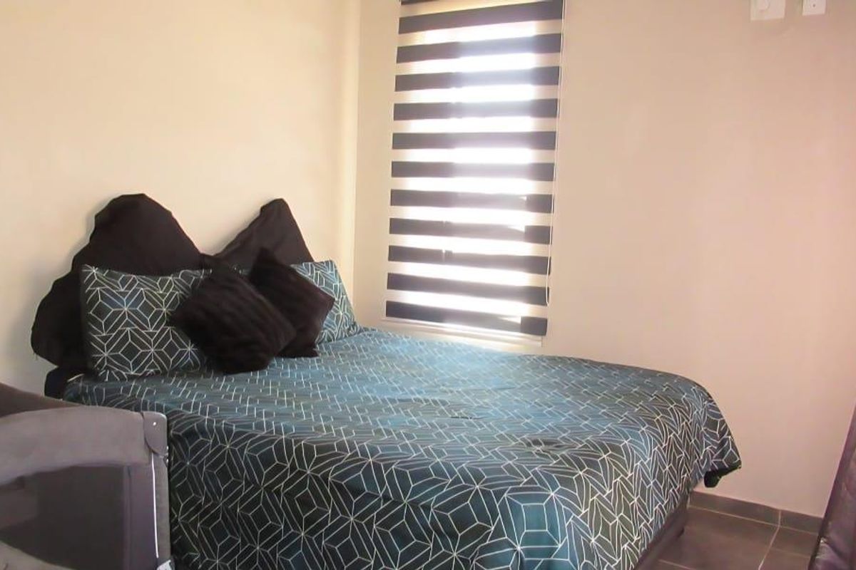 A bedroom featuring tiled flooring and a modern zebra-style roller blind on the window.