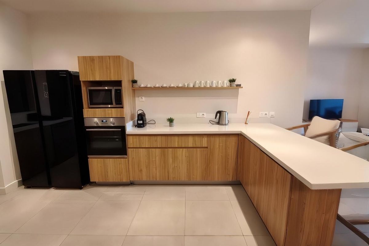 Modern kitchen featuring light wood cabinetry, white stone countertops, integrated oven, and built-in microwave, offering a clean and functional culinary space.