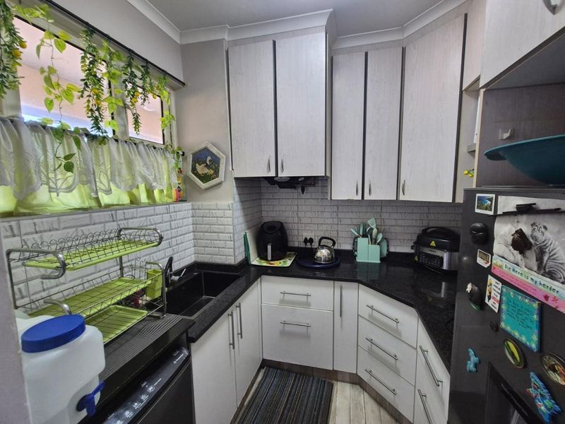 A functional kitchen featuring light-toned cabinetry, dark granite countertops, and a classic subway tile backsplash, providing a clean and practical workspace.