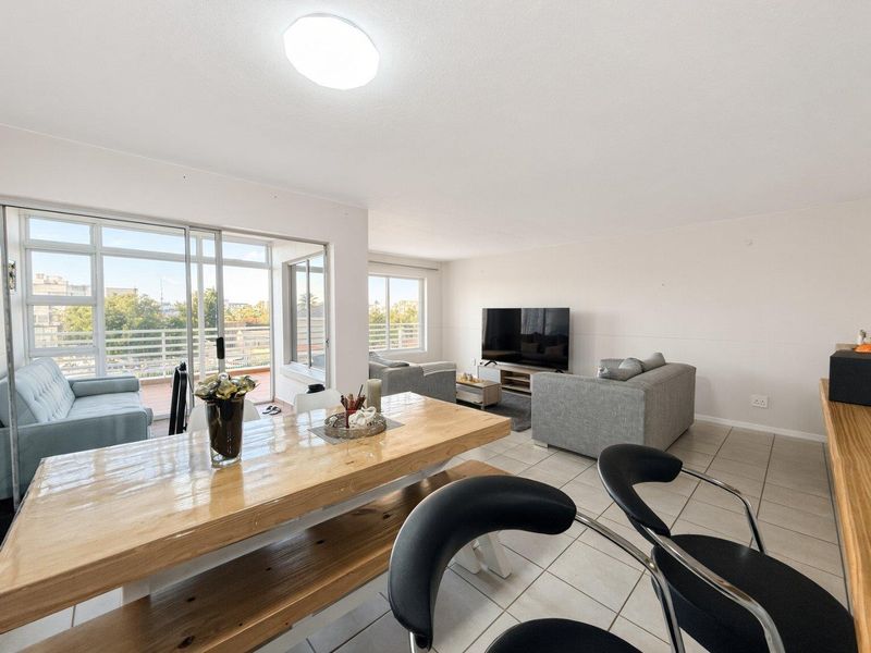 Spacious open-plan living and dining area featuring tiled floors, neutral walls, and large sliding glass doors leading to a private balcony.