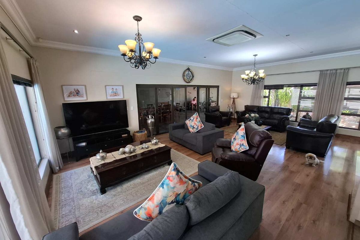 Spacious living room featuring laminate flooring, recessed lighting, ceiling-mounted air conditioning, and sliding glass doors leading to an adjacent dining area.