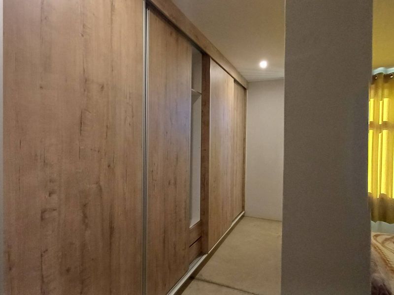 Bedroom featuring a large, modern wood-finish built-in wardrobe with sliding doors and integrated shelving.