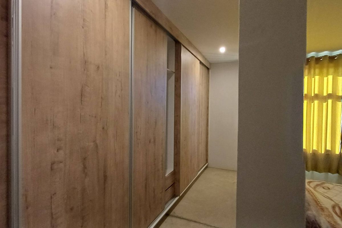 Bedroom featuring a large, modern wood-finish built-in wardrobe with sliding doors and integrated shelving.