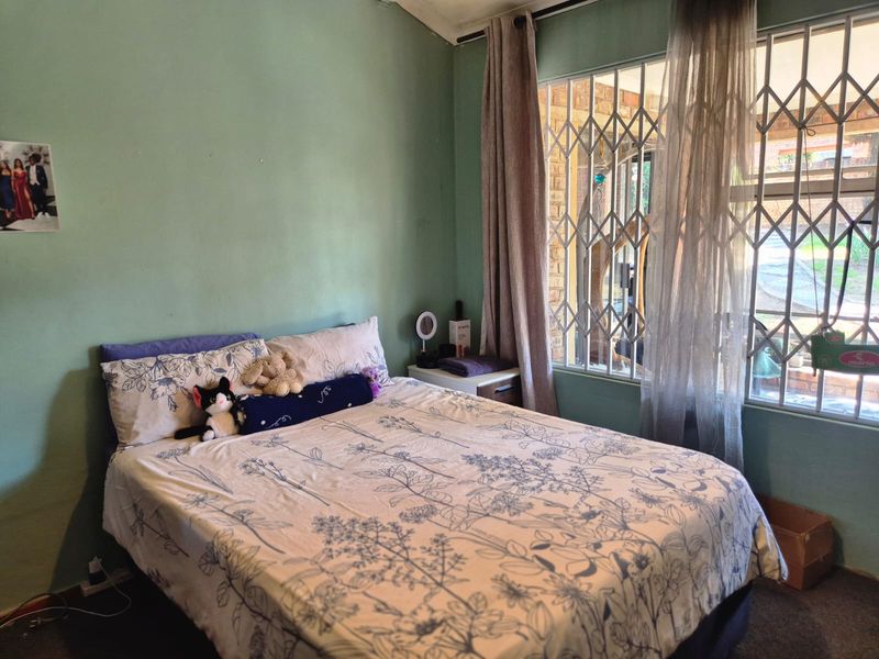 A bedroom featuring a window with a fitted security gate, providing natural light and ventilation.