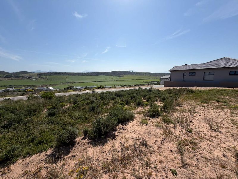 A wide-angle view of the vacant residential land featuring natural vegetation and expansive rural landscape views.