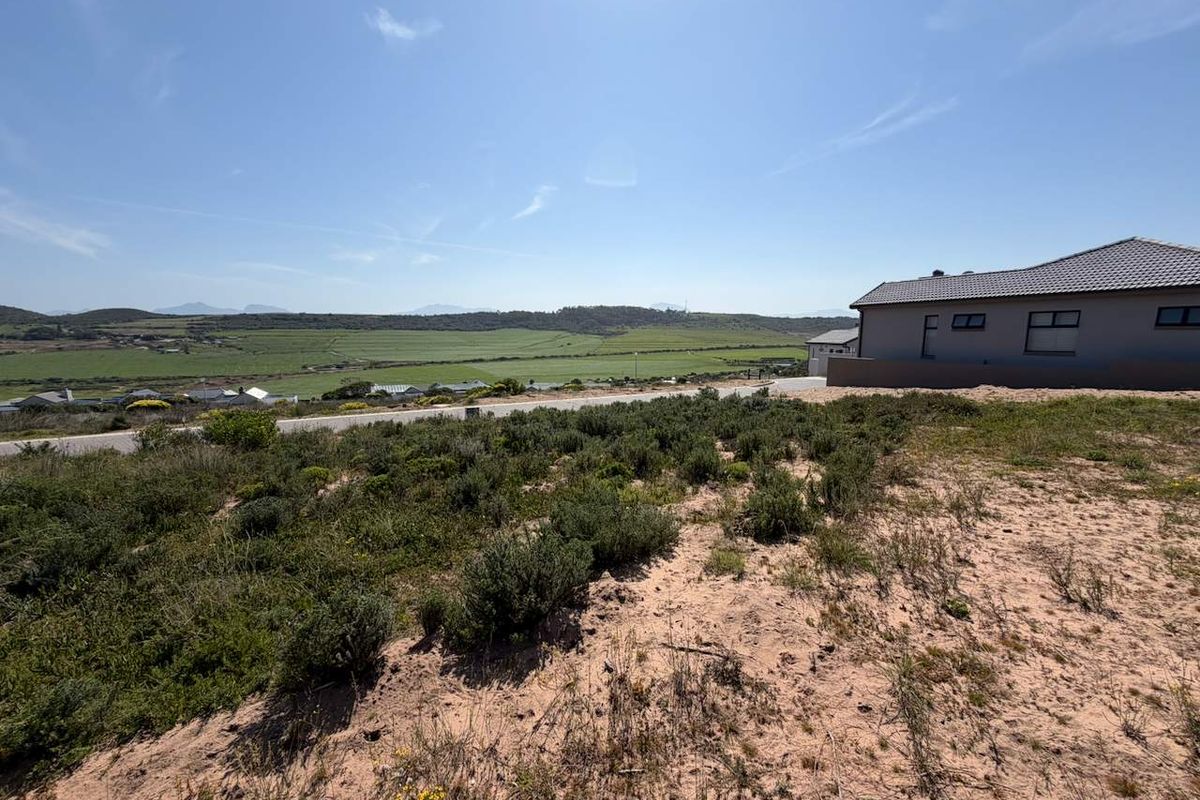 A wide-angle view of the vacant residential land featuring natural vegetation and expansive rural landscape views.