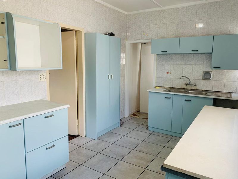 A dated kitchen featuring light blue built-in cabinetry, tiled walls, and tiled flooring, offering a blank canvas for a modern renovation.