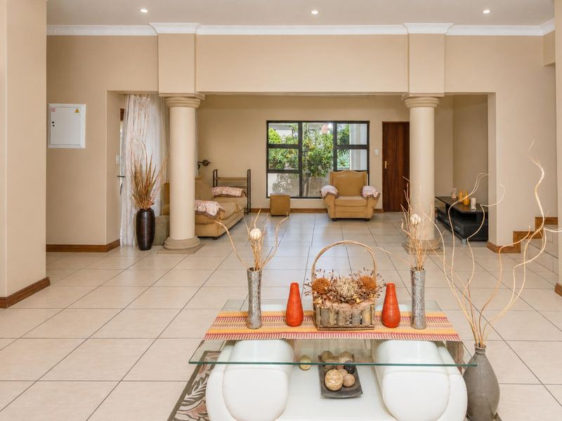 Spacious open-plan living area featuring neutral tiled flooring, decorative columns, and recessed lighting, creating a versatile and well-defined interior space.