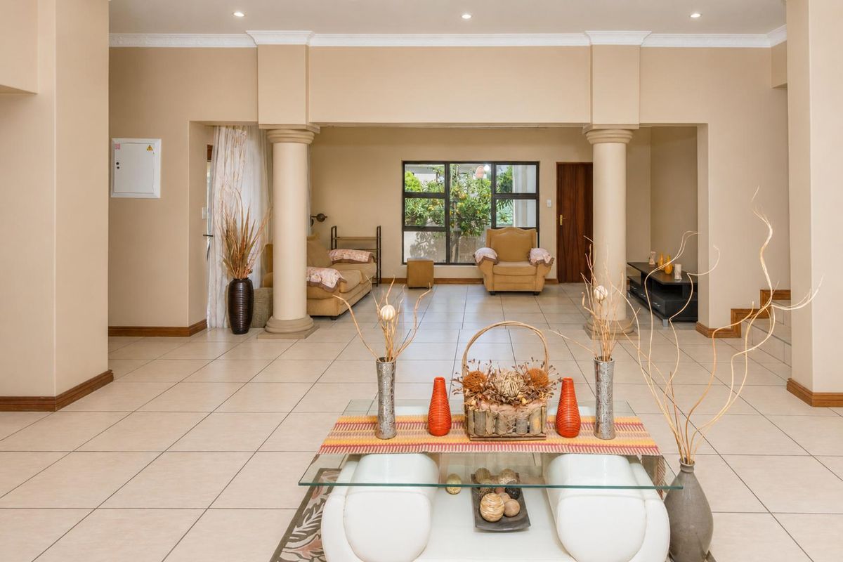 Spacious open-plan living area featuring neutral tiled flooring, decorative columns, and recessed lighting, creating a versatile and well-defined interior space.