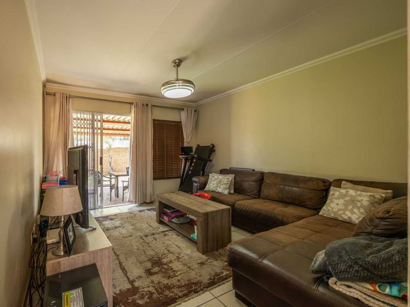 A comfortable living room featuring tiled flooring, a ceiling fan, and a sliding glass door providing access to the outdoor patio area.