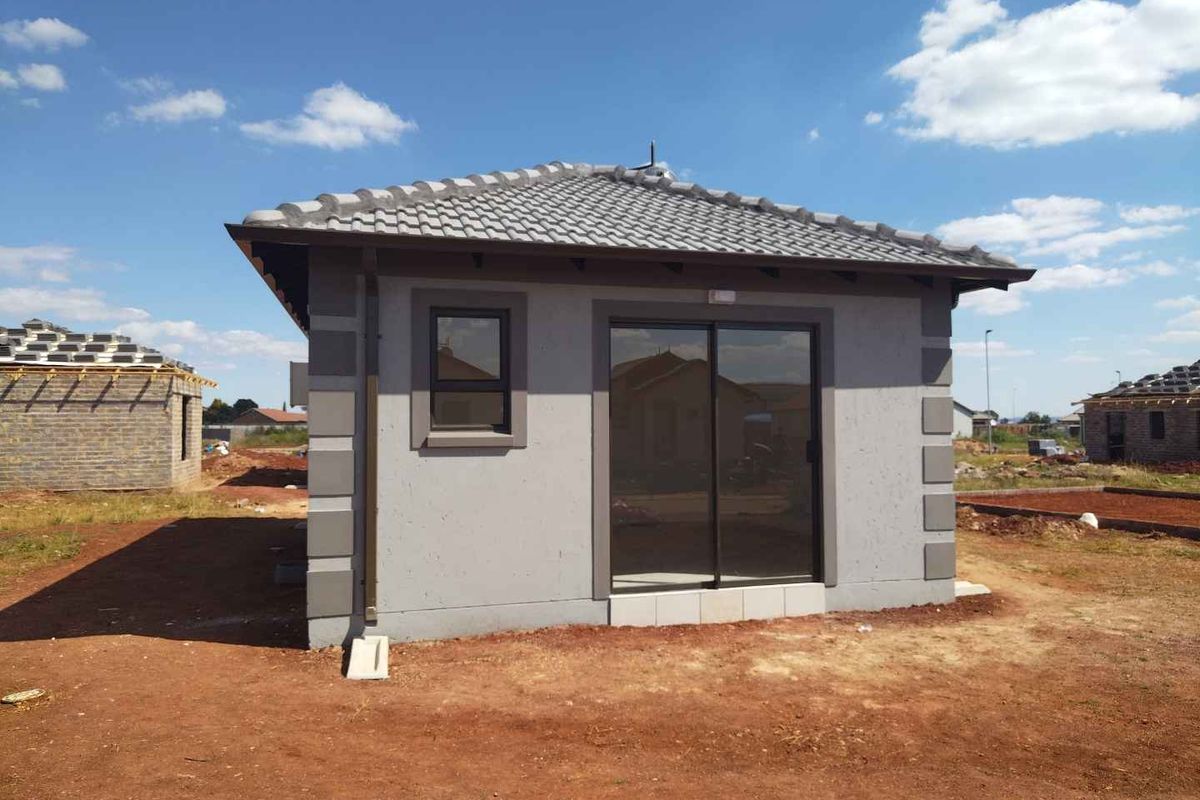 A newly constructed residential unit featuring a tiled roof, plastered exterior walls with corner detailing, and a sliding glass door entrance.