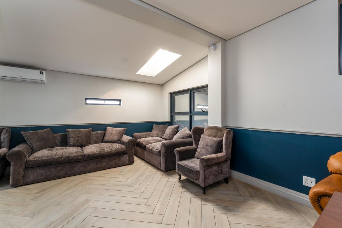 A modern commercial lounge area featuring herringbone wood-look flooring, a skylight, and a wall-mounted air conditioning unit.
